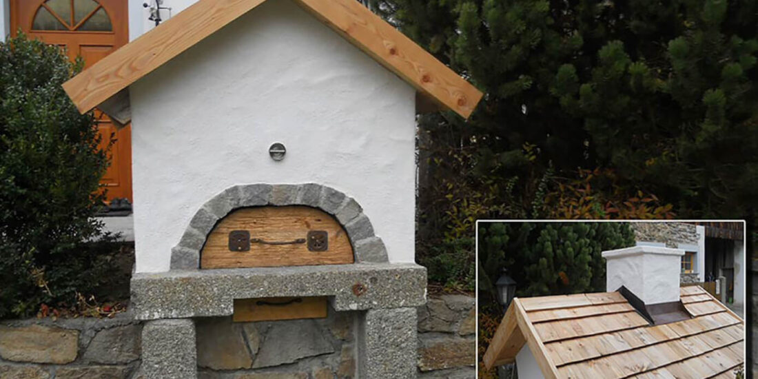 Holbackofen vor einem Haus neben einer Hecke - Holzbackofen Gestaltung